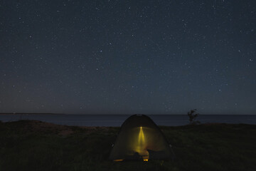 Fototapeta na wymiar Camping with a tent on the shore of the steep Baltic Sea in Paldiski under the starry sky.