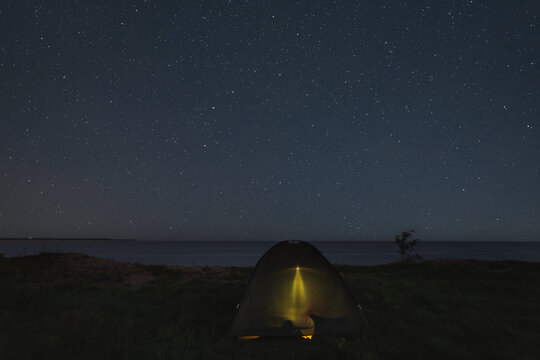 Camping with a tent on the shore of the steep Baltic Sea in Paldiski under the starry sky.