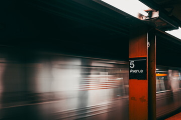 A New York subway train speeds through 5th Avenue station
