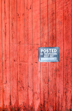Weathered red wood siding with posted, no trespassing sign