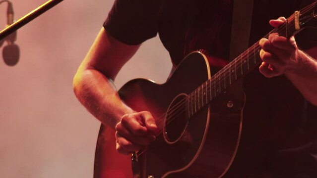guitarist plays acoustic guitar at a concert on the stage