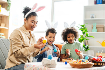 Portrait happy latin family wearing bunny ears painting eggs preparation together for Easter...