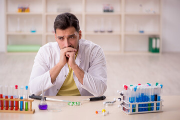Young male chemist sitting at the lab - 744847241