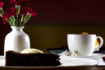 Brown homemade cake and coffee on white tablecloth in restaurant