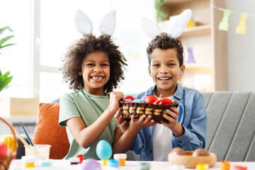 Portrait funny cute latin kids holding colorful eggs celebration Easter looking at camera at home 