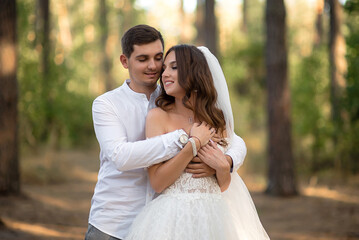 Fototapeta premium The young groom and bride, in the forest, lovingly embrace
