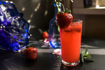 Strawberry juice in a glass with fresh strawberries on a dark background