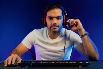 Smart gaming streamer looking at camera with trendy pose, passing the level of online game user on...