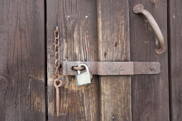 Old lock at wooden door mixed with a modern padlock.