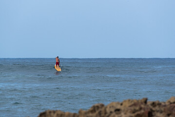 Stand up paddler waiting for waves to surf in the ocean - 744854001