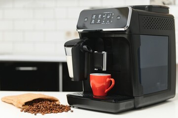 blurred background of kitchen and coffee machine with red cup and space for you