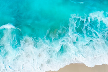 Aerial view of turquoise ocean waves meeting a sandy beach.