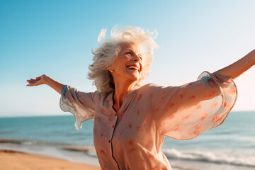 A joyful senior woman with a flowing scarf on a sunny beach.