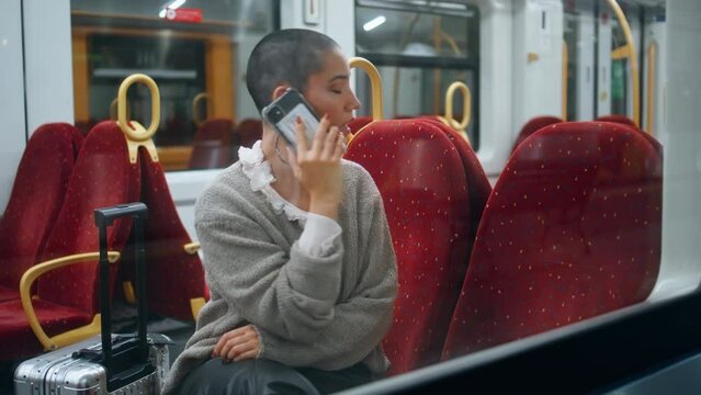 Tired tourist calling mobile phone in train. Short hair woman talking smartphone