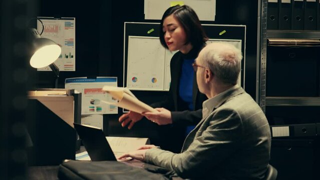 Detectives team search for missing persons or unsolved cases in archived records, looking for connection between investigations. Private agents working with forensic evidence in archive. Camera B.