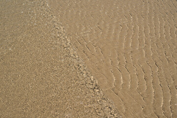 At the beach, gentle ripples caress sand and water, creating a serene and soothing atmosphere
