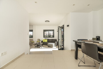 Living room on two levels of a single-family home with smooth white painted walls and metal carpentry of black aluminum and glass windows and doors