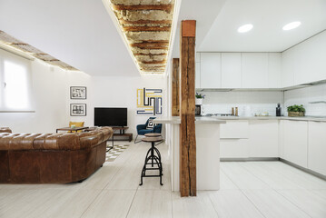 A nice loft apartment with contemporary design furniture and a large brown leather chester sofa,...