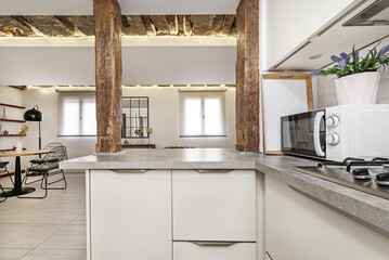 A kitchen in an apartment with contemporary industrial style decoration with a serving hatch between antique wooden columns