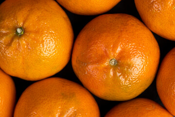 a large number of orange citrus fruits on a black slate surface