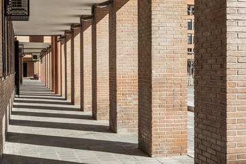 Passage in the basement of a building with shadows from the pillars and vanishing point