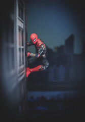 Naklejka premium NEW YORK USA, FEB 25 2024: friendly neighborhood spiderman crawling on the side of a building - Hasbro action figure