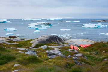 A place to rest.  Bench, kayaks and icebergs.  Illulisat, Greenland.