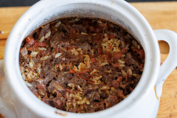 Giouvetsi - traditional Greek and Cretan baked dish with beef and orzo pasta in tomato sauce in baking pot, top view