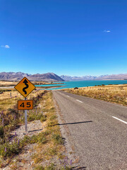 Explore the scenic highway around Mount Cook, winding past Lake Pukaki amidst New Zealand's majestic mountain landscape.