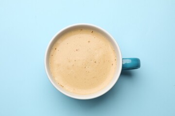 Fresh coffee in cup on light blue background, top view
