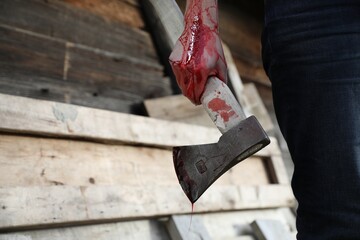 Man holding bloody axe outdoors, closeup. Space for text