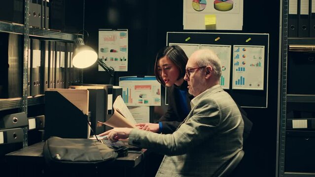 Team members cross reference data to track down potential suspect, using archived records and forensic evidence reports. Officers uncover crucial information to help solve legal case. Camera A.