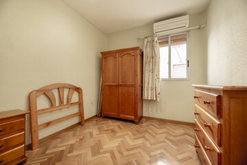 Half empty room with some varnished sweet pine wood furniture, shiny varnished parquet floor and walls painted in an undefined color