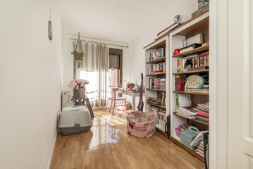 Bedroom with custom wardrobe with white lacquered wooden doors and varnished oak floor and balcony at the back and shelves of the same material full of books and accessories