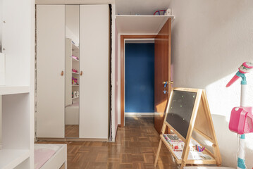 Bedroom with normal wooden wardrobe integrated into a hole in the wall, varnished oak floor