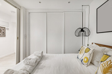 Bedroom with a double bed with a peculiar wooden structure, modern decoration, cushions with yellow...