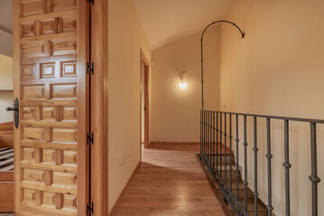 Interior stairs of a duplex residential home with wooden floors and Castilian-style pine panel doors