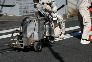 A scene of road marking line construction. Work to clarify the center line of the road with white...