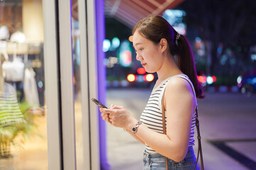 Happy beautiful Asian smart and good looking woman walking in the community mall at night.