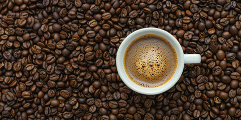 Top view of a fresh cup of coffee on a bed of roasted beans