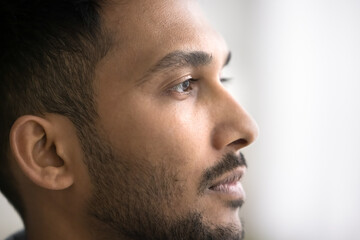 Close up photo of young thoughtful Indian man looking into distance, deep in thoughts, ponder,...