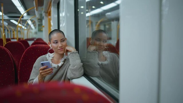 Relaxed girl commuting train listening music by earbuds. Woman sitting railway