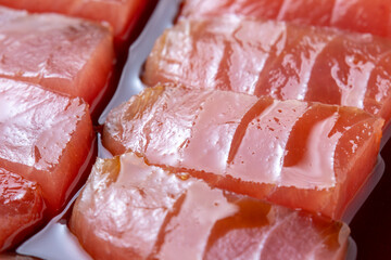 漬けまぐろ調理シーン。マグロ切り身を漬けだれに漬ける。
