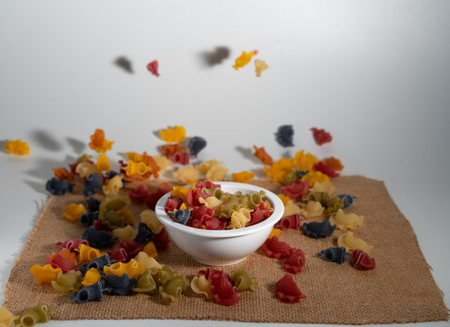 Falling raw multocolor  Creste di gallo, uncooked Italian Pasta on bowl and sackcloth