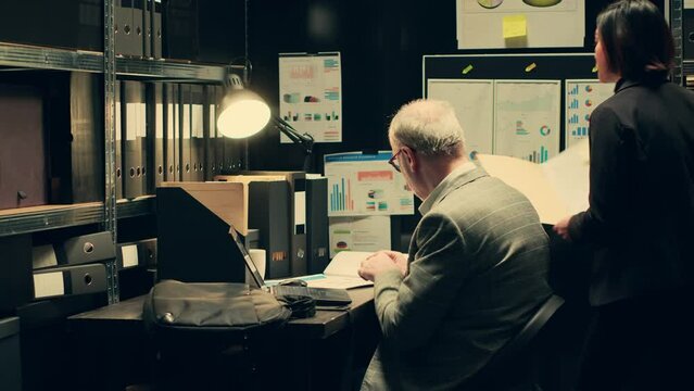 Detectives team search for missing persons or unsolved cases in archived records, looking for connection between investigations. Private agents working with forensic evidence in archive. Camera A.