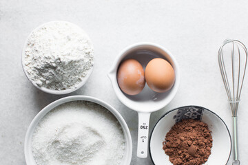 mise en place of ingredients for making brownies, top view of sugar, eggs, butter, flour cocoa...