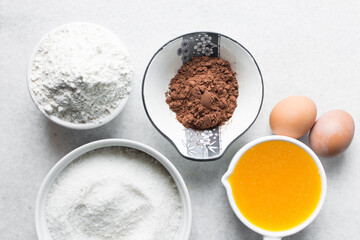 mise en place of ingredients for making brownies, top view of sugar, eggs, butter, flour cocoa...