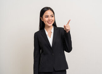 Young beautiful asian business woman smiling pointing finger to blank space for advertise text on isolated white background. Attractive Latin Female around 25 in suit portrait shot in studio.