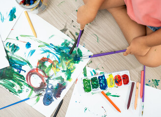 Happy moment little cute girl creating and water color painting activity with paint brushes on frame canvas at living room. Kids activity. Child physical, Emotional, Cognitive development concept.
