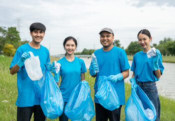 Happy volunteer people group charity with garbage bags cleaning up in park. Corporate social responsibility and society activity for Environment . Ecology and CSR concept.